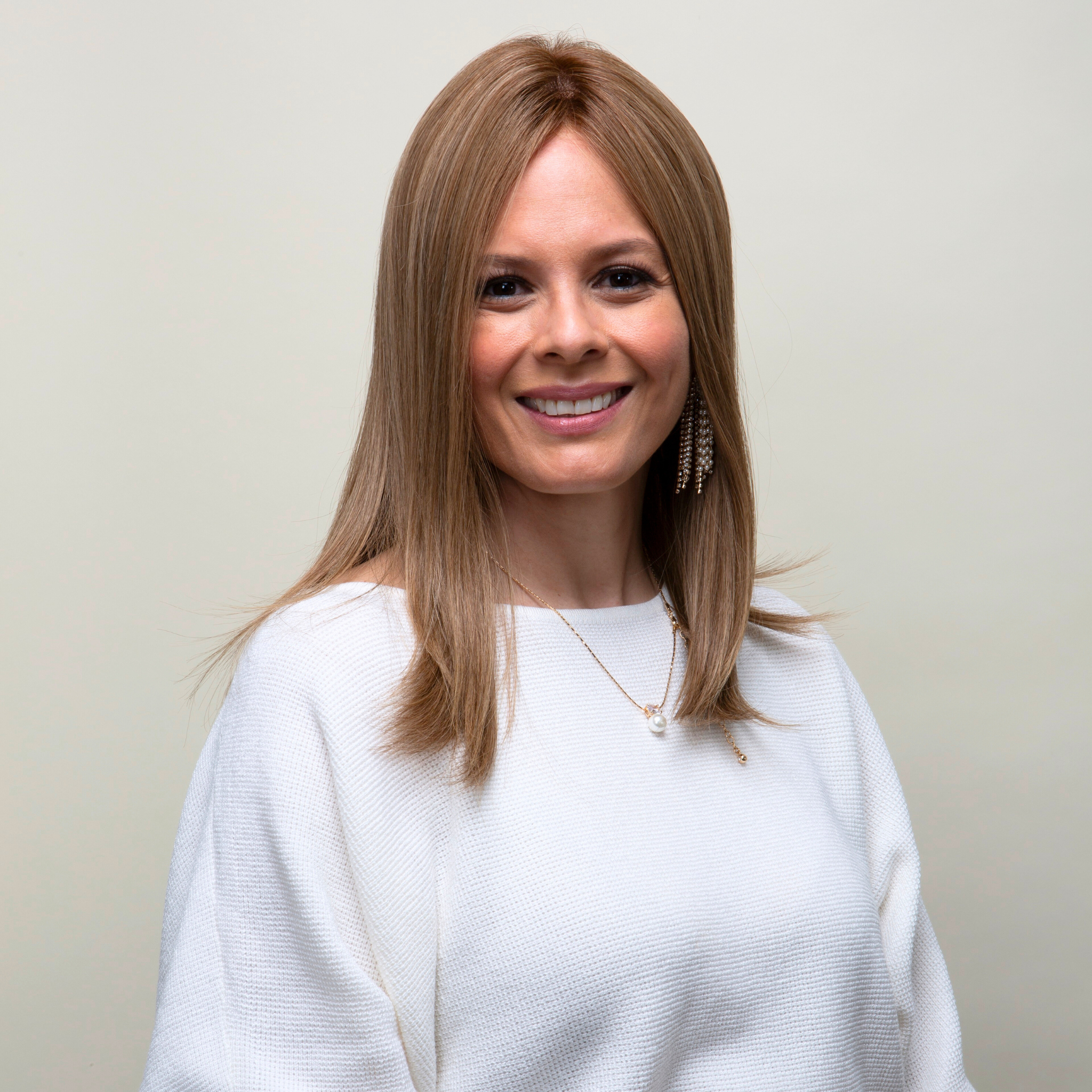 Woman with extra large base, french top, lace front hair topper, wearing a white sweater against a plain background.